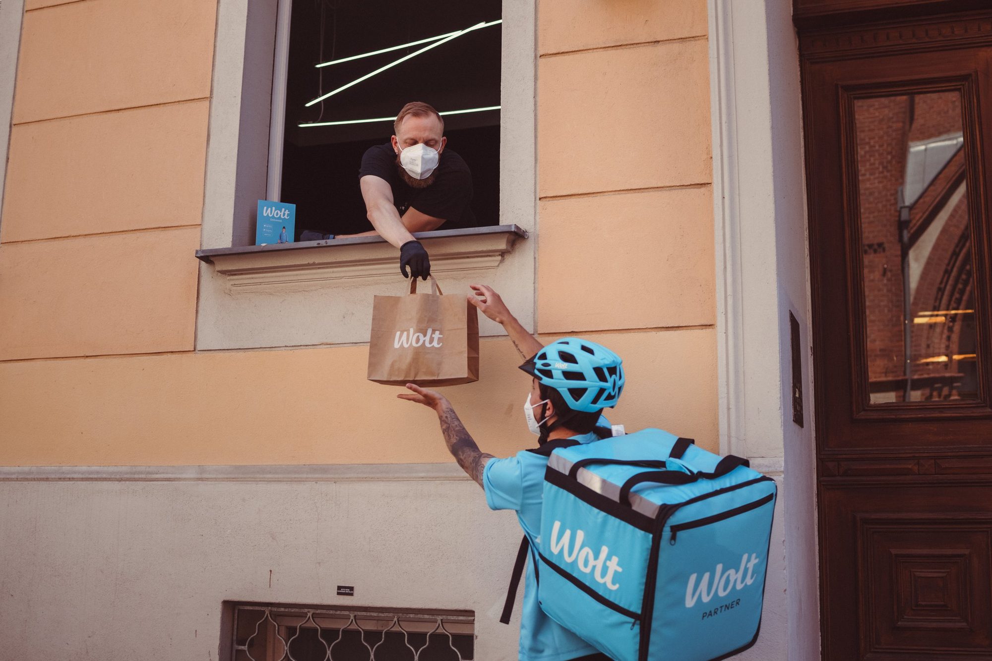 Mikko Koskinen, co-founder of Kyrö Distillery, passes an order to a Wolt courier from the company's Berlin store, 2021